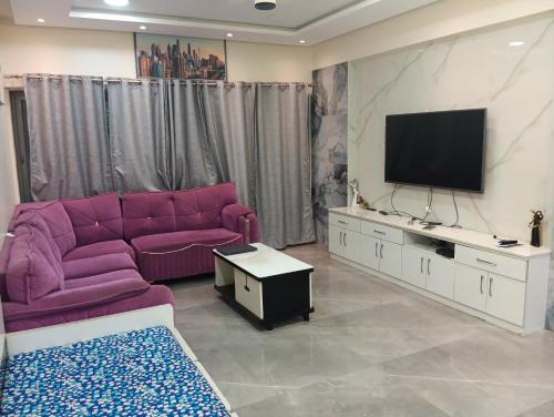 a living room with a purple couch and a tv at Kumar Papillon in Pune