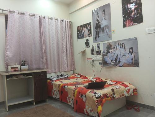 a bedroom with a bed and a desk and pictures on the wall at Kumar Papillon in Pune