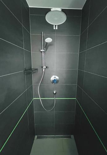 a shower with a hose in a black bathroom at Haus Calmsailing in Börgerende-Rethwisch