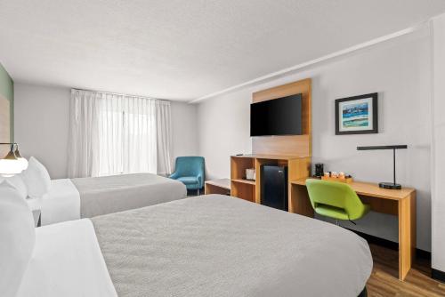 a hotel room with two beds and a desk and a television at Quality Inn Orlando Near International Drive in Orlando