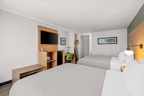 a hotel room with two beds and a flat screen tv at Quality Inn Orlando Near International Drive in Orlando