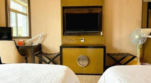 a hotel room with a television and a bed at Jiaxin Conifer Hotel Shunde in Shunde