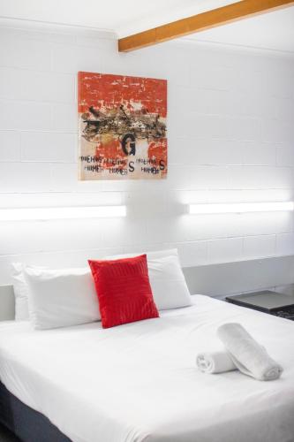 a bedroom with a white bed with a red pillow at The Grampians Motel in Halls Gap
