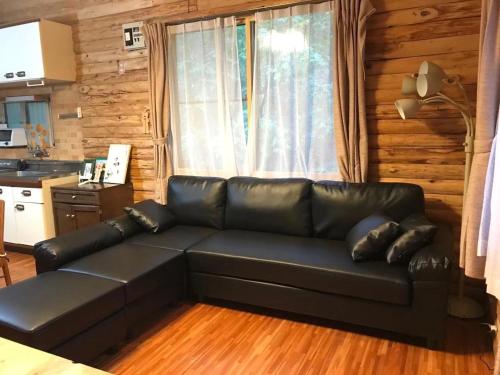 a living room with a black leather couch in a kitchen at Mori no Komei campsite - Vacation STAY 04499v in Kita-karuizawa