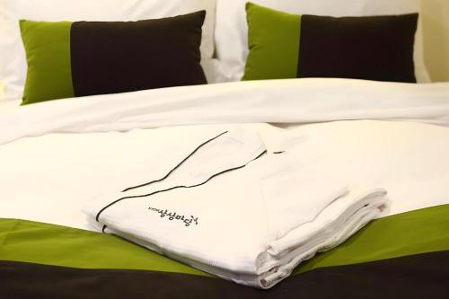a white blanket on a bed with green pillows at KT&G Sangsangmadang Chuncheon Stay (Korea Quality) in Chuncheon