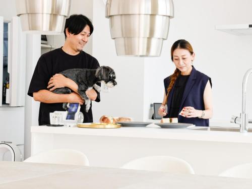 a man and a woman standing in a kitchen with a dog at Seagull east coast Awaji - Vacation STAY 21943v in Awaji
