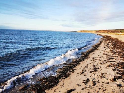 a beach with a wave breaking on the shore at 6 person holiday home in Gørlev in Gørlev