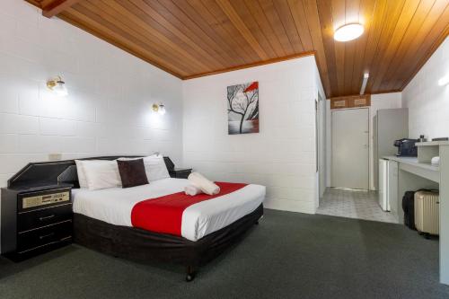 a bedroom with a bed with a red and white blanket at The Grampians Motel in Halls Gap