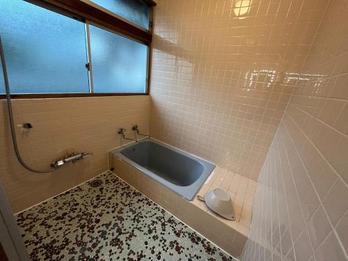 a bathroom with a tub with a window and a tile floor at CalmbaseRIVER - Vacation STAY 22009v in Numazu