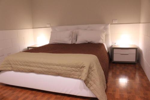 een slaapkamer met een groot bed met 2 nachtkastjes bij Gazebo Rooms in Margherita di Savoia
