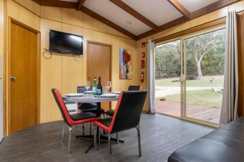 a dining room with a table and chairs and a television at The Grampians Motel in Halls Gap