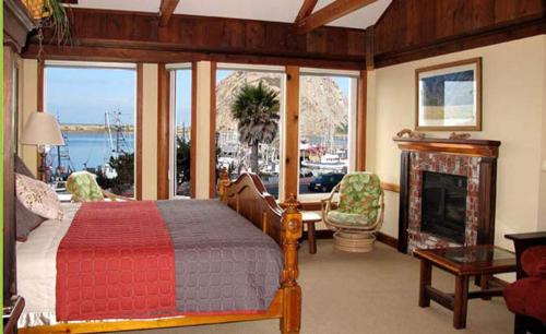 a bedroom with a bed and a fireplace with a view at Front Street Inn and Spa in Morro Bay
