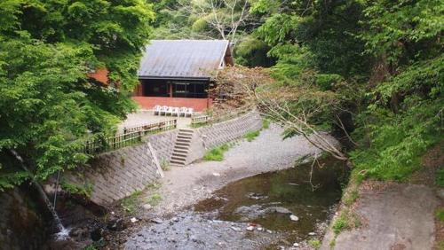 a building with stairs next to a river in a forest at Toukaen campsite - Vacation STAY 23959v in Uenohara