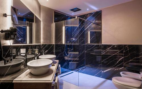 アルペ・ディ・シウージにあるHotel Rosa Eco Alpine Spaのトイレが3つあり、青いタイル張りの壁があるバスルーム
