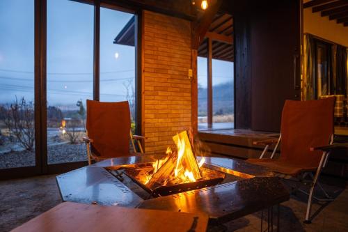 a fireplace in a room with chairs and a table at Sense of wonder Yufudake Sanroku Glamping Resort - Vacation STAY 41962v in Yufuin