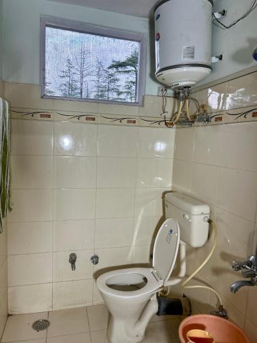 a small bathroom with a toilet and a window at Chopra Home Stay in Chamba