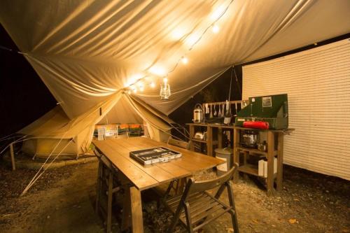 a tent with a wooden table and chairs in it at Shirasu-Ojiro FLORA Campsite in the Natural Garden - Vacation STAY 00652v in Shirasu