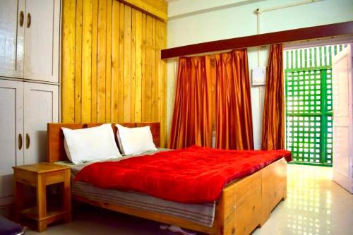 a bedroom with a bed with a red blanket at Chopra Home Stay in Chamba