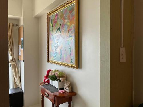 a painting on a wall next to a table with flowers at Recharge Chamber Simoy in Kaybagal