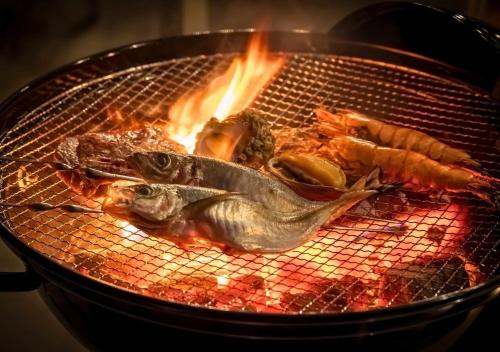 a grill with fish and other foods on fire at Glamping Base IZUMO "Lakeside Hot Spring Hotel Kun - Vacation STAY 42016v in Izumo