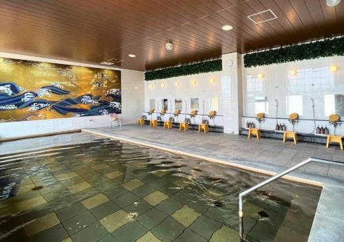 a swimming pool with tables and chairs in a building at Glamping Base IZUMO "Lakeside Hot Spring Hotel Kun - Vacation STAY 42016v in Izumo