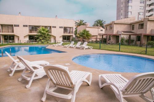 un grupo de sillas de césped y una piscina en Cabañas Las Añañucas IV, en La Serena