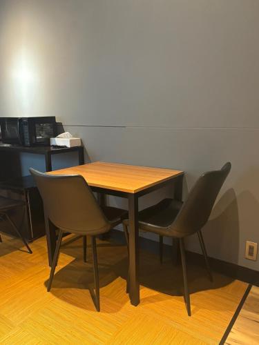 a wooden table and two chairs in a room at P-Stay 広島八丁堀 201号室 in Ōsukachō