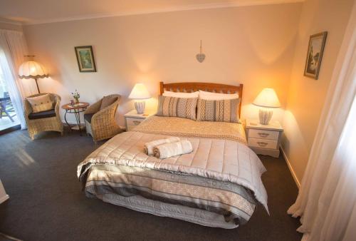 a bedroom with a bed with two lamps and a chair at Rolling Hills Country Stay B&B in Tauranga