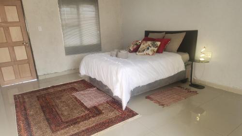 a bedroom with a bed with white sheets and red pillows at GenAyah Hotel & Safari in Mtimba