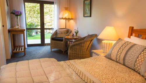 a bedroom with a bed and a table with a chair at Rolling Hills Country Stay B&B in Tauranga