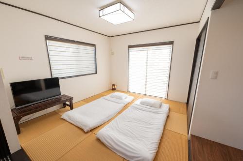 two beds in a room with a flat screen tv at Twilight Hills - Vacation STAY 32702v in Motobu