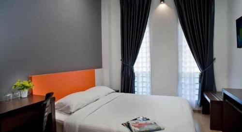 a bedroom with a bed and a desk and a window at Big Orange Hotel Jitra in Alor Setar