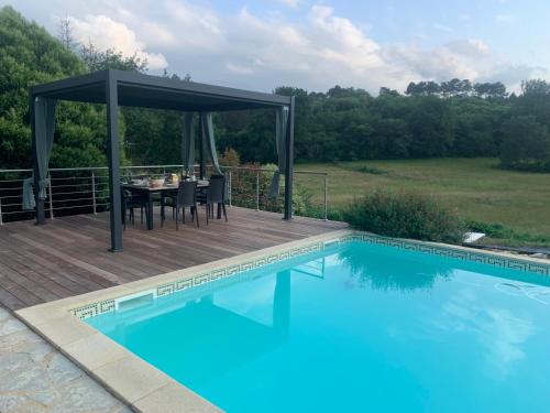 a deck with a table and chairs next to a swimming pool at La Ferme de Borie in Fumel
