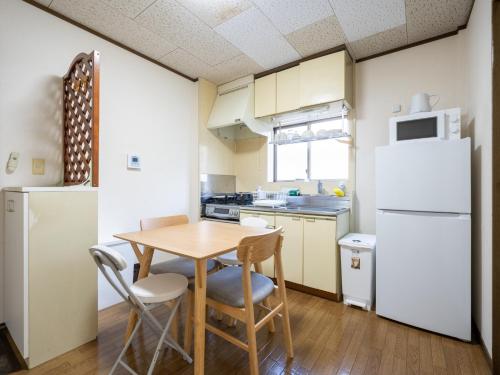 a small kitchen with a table and a white refrigerator at maison elegance - Vacation STAY 15798 in Tokyo