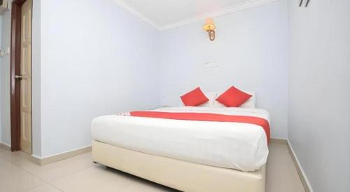 a white bedroom with a white bed with red pillows at OYO 969 Hotel Pantai View in Labuan
