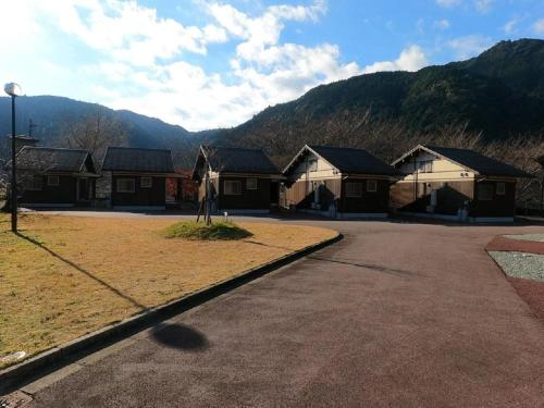 a row of houses with mountains in the background at Hisetsu no Taki Campsite - Camp - Vacation STAY 42072v in Ōzato