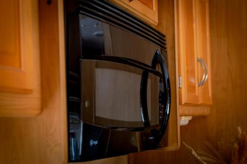 a black microwave oven in a kitchen with wooden cabinets at MUUN Beach Club in Ciudad del Carmen