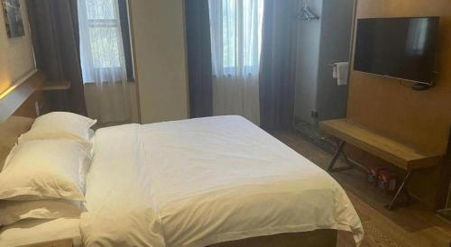 a bedroom with a white bed and a flat screen tv at James Joyce Coffetel Xian Big Goose Pagoda Tang Paradise Branch in Xi'an