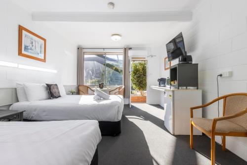 a hotel room with two beds and a television at The Grampians Motel in Halls Gap