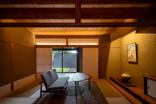 a living room with a chair and a table at Momoyama Onsen Tsukimikan in Kyoto