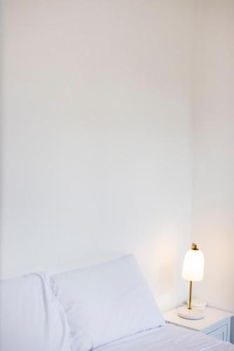a white bedroom with a bed and a lamp at The Grampians Motel in Halls Gap