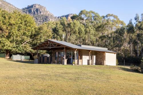 a building in a field with mountains in the background at The Grampians Motel in Halls Gap