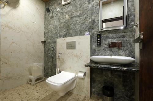 a bathroom with a white toilet and a sink at Airport Hotel Bright Buzz in New Delhi