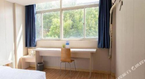a bedroom with a desk in front of a window at 7 Days Inn Changzhou Yancheng Technology Metro Station in Changzhou