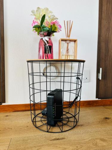 a black wire basket table with a vase and flowers at Shirakata Token Residence 701 - Vacation STAY 76938v in Matsue