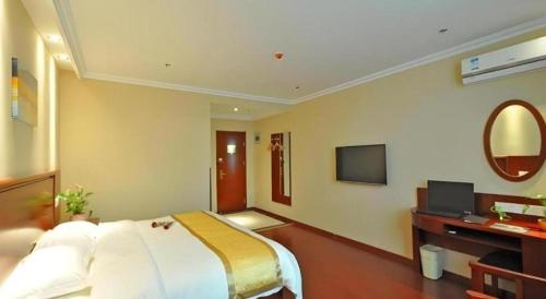 a bedroom with a bed and a desk and a television at GreenTree Inn Linxi International Convention Center Express Hotel in Linyi