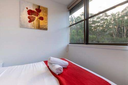 a bedroom with a red and white blanket and a window at The Grampians Motel in Halls Gap