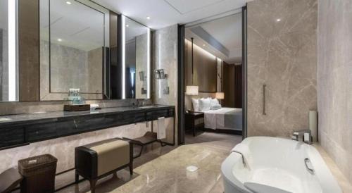 a bathroom with a sink and a toilet and a bed at Golden Eagle Summit Hotel Kunshan in Suzhou