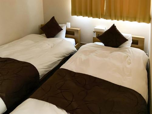 a room with two beds with white sheets and black pillows at Asama no Iori - Vacation STAY 01001v in Fujiyoshida