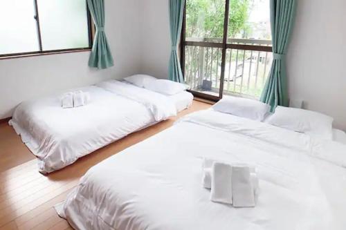 three white beds in a room with windows at Itsukaichi First Villa Hiroshima - Vacation STAY 15653 in Hiroshima